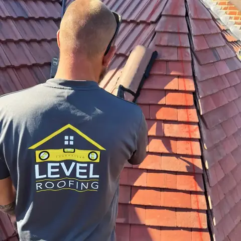 A Level Roofing roofer in a branded T-shirt bedding hip tiles