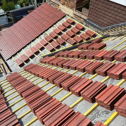 New red tiles loaded out in stacks on battens and breathable membrane