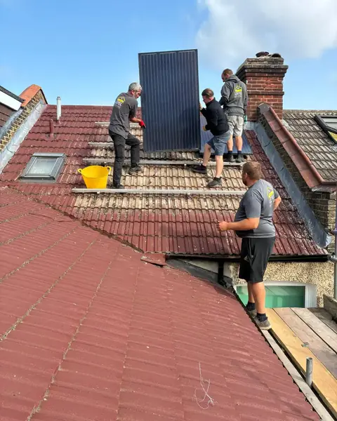 Level Roofing team on a Bromley roof of old painted tiles, lifting off a solar panel