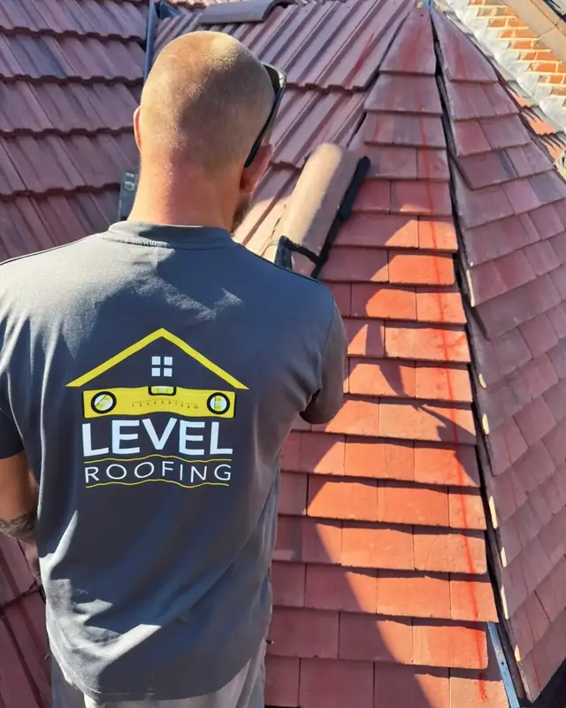 A Level Roofing roofer bedding hip tiles on a newly tiled red roof