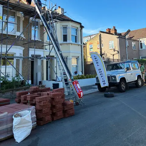Scaffold, a tile hoist and stacks of new tiles outside a terraced house in Bromley