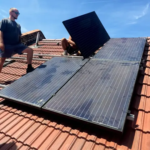 The Level Roofing team refitting black solar panels on the new red tiled roof