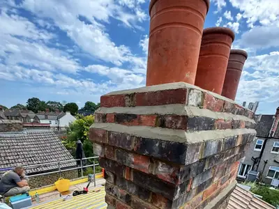 A rebuilt brick chimney stack with three terracotta pots in Bromley