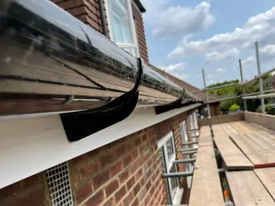 A new black gutter and white fascia fitted under a tiled roof